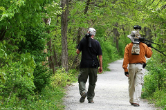 Two people walking in the woods carrying cameras