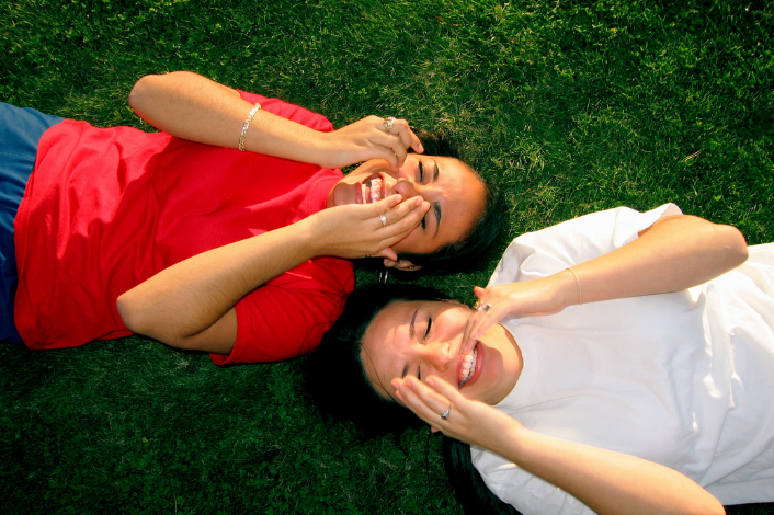 Two women laughing while lying on the grass