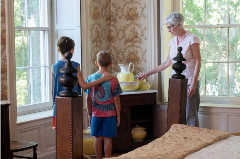 Two children and a tour guide describing a antique vase