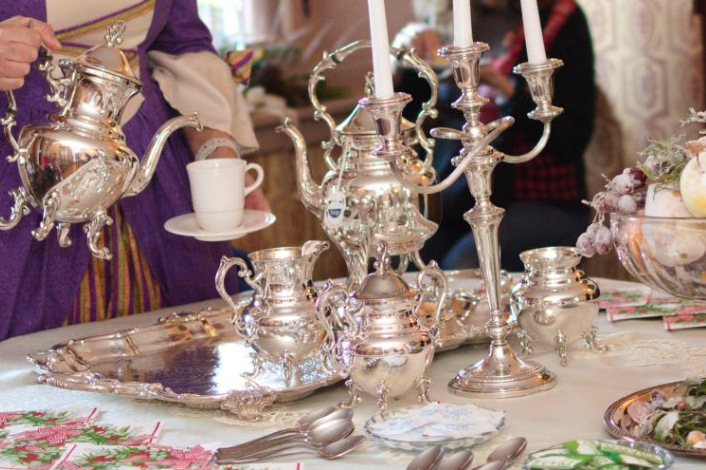 Costumed Attendant pouring tea from a silver teapot at an elegant table