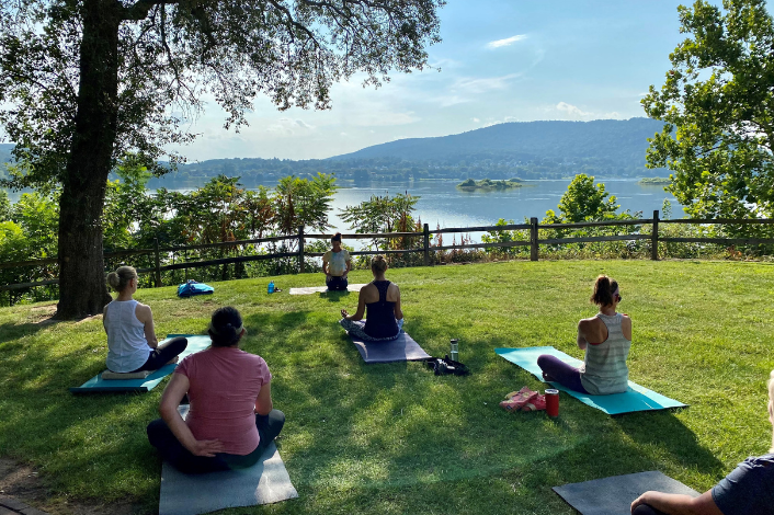 adults on yoga mats outdoors with a view of the river