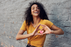 Woman making a heart with her hands over where her heart would be