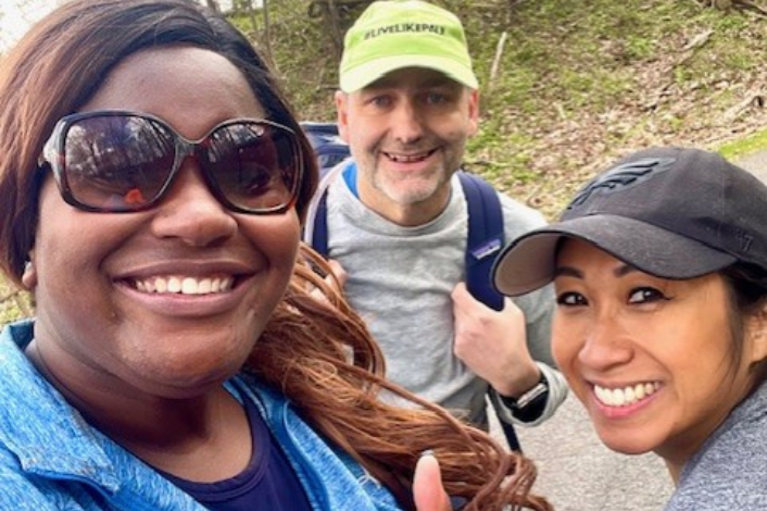 Three volunteers smiling working in a park on cleanup