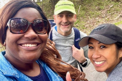 Three volunteers smiling working in a park on cleanup
