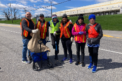 Group of volunteers in orange vest posing next to the road