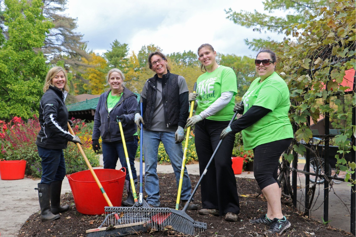 A group of volunteers with rakes brooms and shovels cleaning up at Wildwood  Park