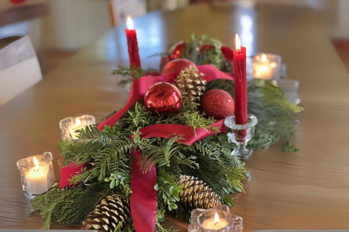 Centerpiece on a table made with natural greens and pinecones with a red ribbon