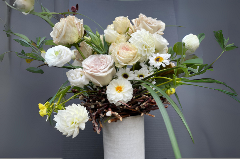 Roses and other flowers in a vase with a created bird's nest